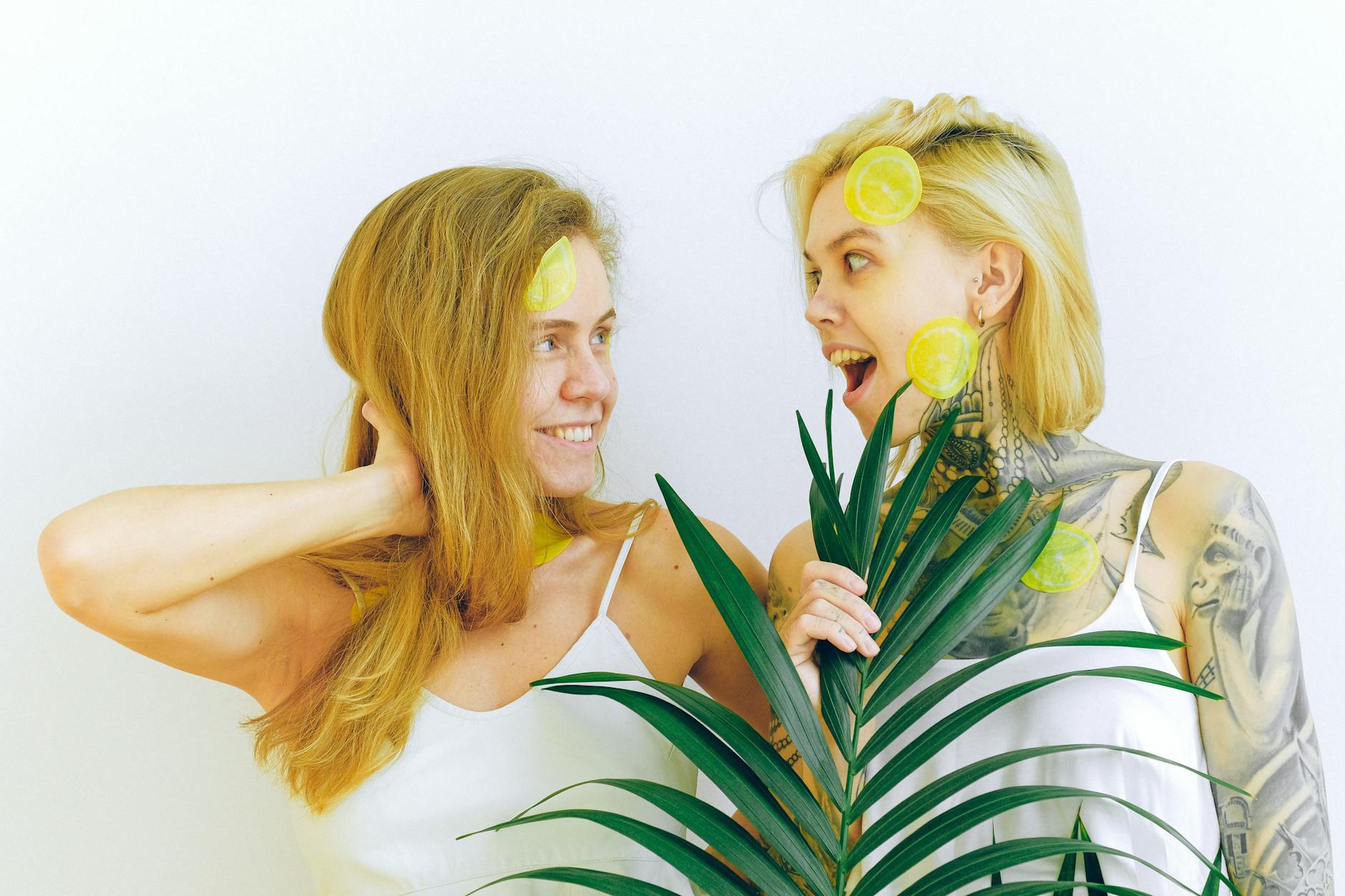 Duas mulheres sorrindo, compartilhando um momento de alegria e diversão com frutas cítricas