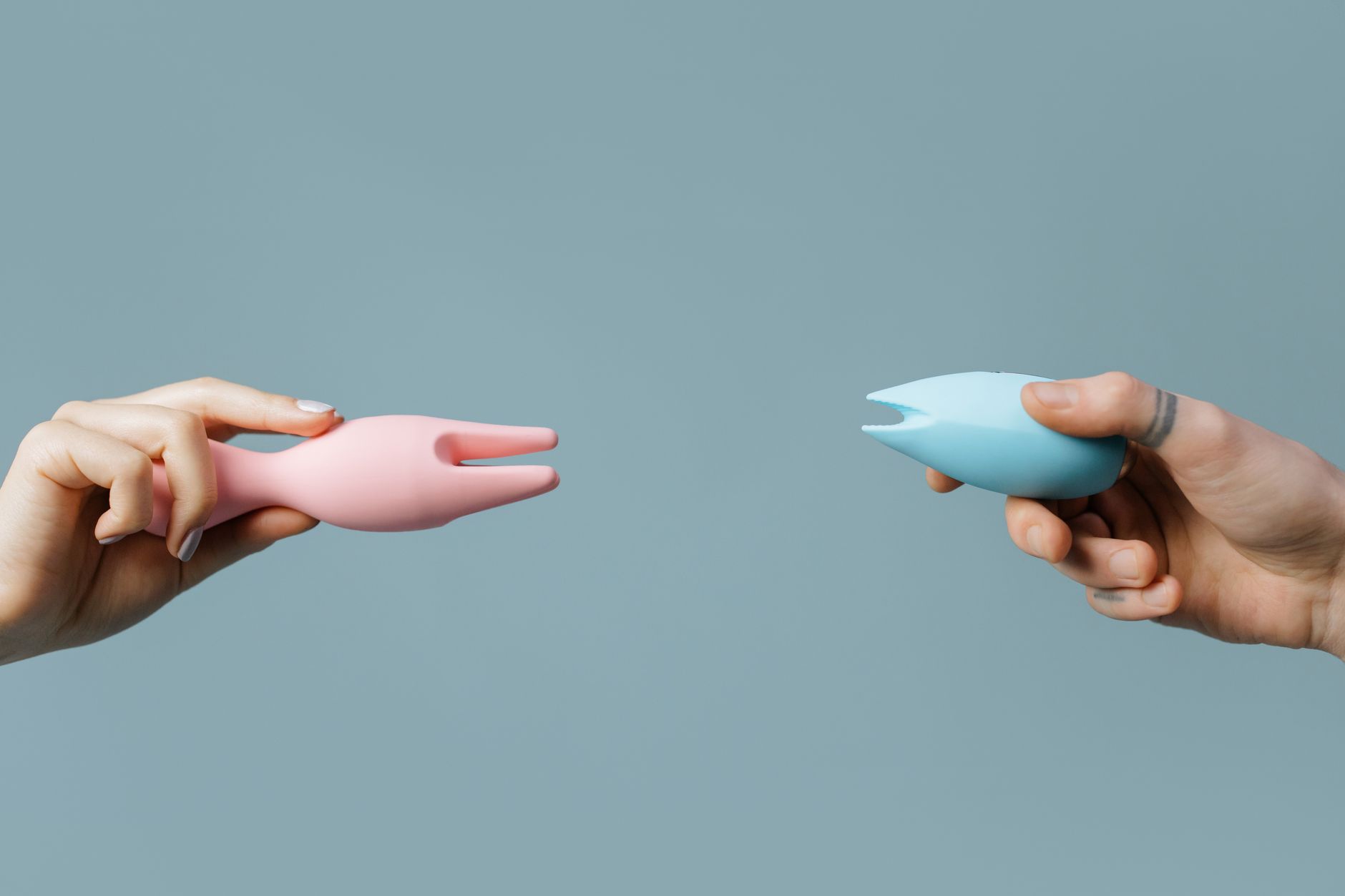Uma mão segurando um vibrador de silicone contra um fundo roxo sólido, promovendo autossatisfação e sexualidade