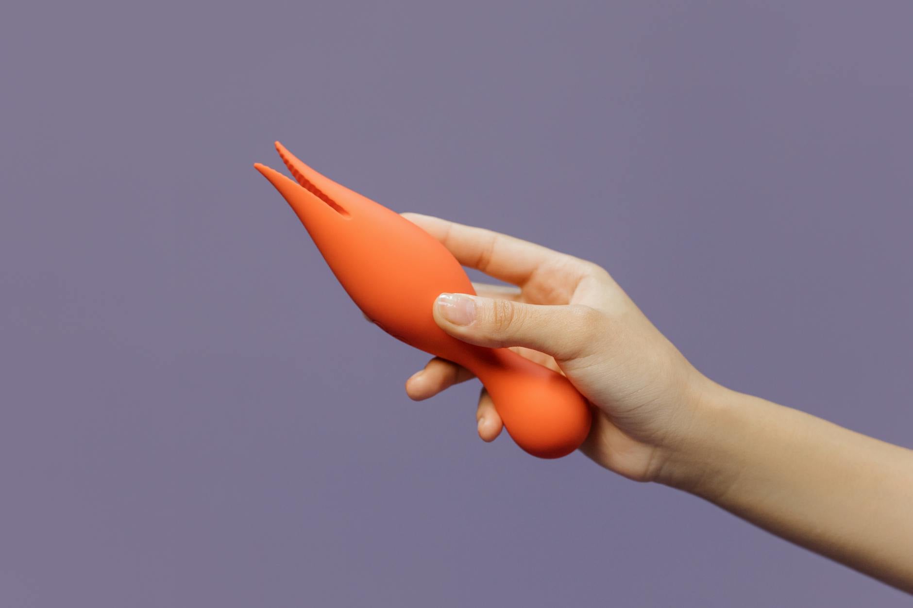 Close-up de mãos segurando um vibrador de limão contra um fundo minimalista roxo, mostrando modernidade e sensualidade reconstruída