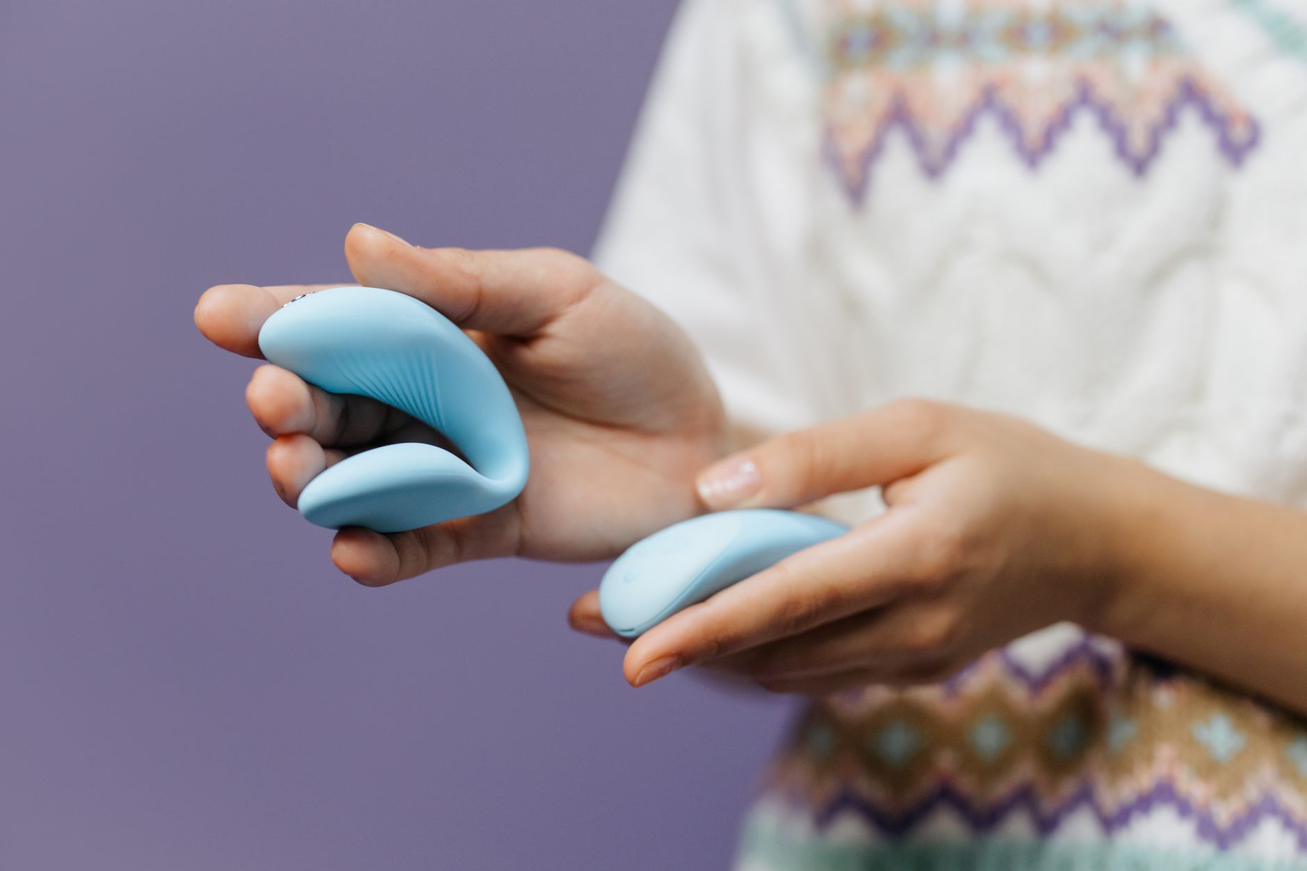 Mão segurando um vibrador de limão elegante contra fundo roxo, representando prazer solo e autoexploração