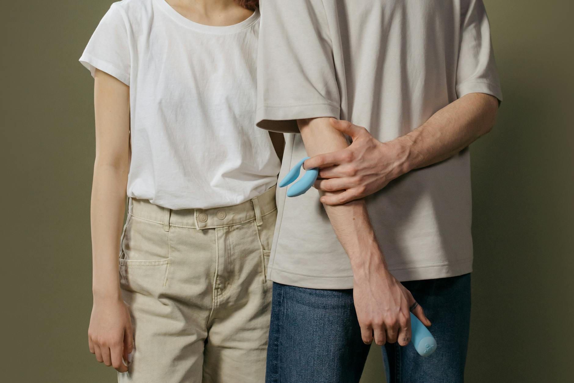 Vibrador de silicone azul sendo segurado em uma mão contra fundo roxo